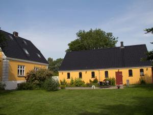 una casa amarilla con techo negro en un patio en Murermester Madsens Villa, en Otterup