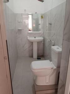 a white bathroom with a toilet and a sink at Happy Stay Holiday Inn in Hikkaduwa