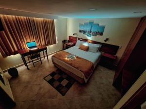 a bedroom with a bed and a desk with a laptop at Hotel Estación Sabana in Zipaquirá