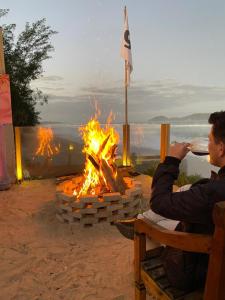 a man taking a picture of a fire pit at Graffi Beach House in Florianópolis