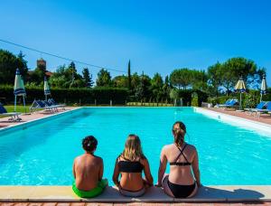 um grupo de três pessoas sentadas em frente a uma piscina em Podere Simonetta - A8 em Cecina