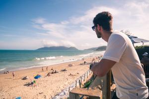 a man standing on a fence at the beach at Graffi Beach House in Florianópolis