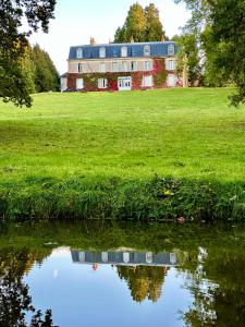 una casa grande en un campo con un estanque en Château de Belleaucourt, 