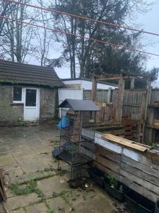 Spacious 1 bedroom en-suite, kitchen and garden space في إلفورد: قفص طيور في فناء بجوار سياج