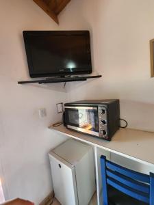 a microwave sitting on a counter with a tv on a wall at Los Abuelos Apart in General Pico