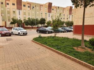 a parking lot with cars parked in front of a building at Mooi appartement, Route el Aounia Oujda in Oujda