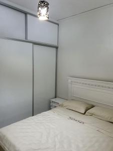 a bedroom with a white bed with a light above it at Mooi appartement, Route el Aounia Oujda in Oujda