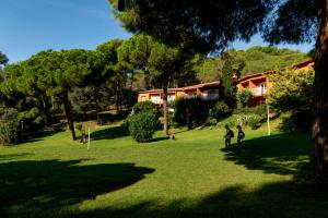two people walking in a park with a house in the background at Albamar Apartaments in Lloret de Mar