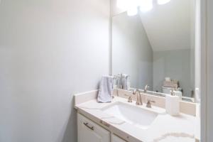 a white bathroom with a sink and a mirror at Bright Townhouse Downtown Lake Charles in Lake Charles