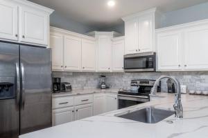 a kitchen with white cabinets and a stainless steel refrigerator at Bright Townhouse Downtown Lake Charles in Lake Charles