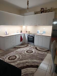 a kitchen with white cabinets and a rug at Zorbas House in Dhesfína