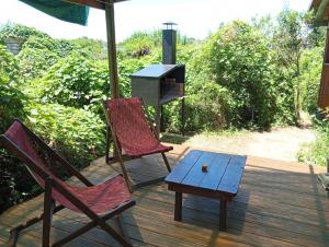 2 sillas y una mesa en una terraza con parrilla en Sietevestidos Casa Ecológica - Punta Negra, en Punta Colorada