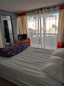 a bedroom with a bed and a large window at Depto primer piso Quisco Norte in El Quisco