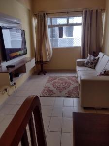 - un salon avec un canapé et une télévision dans l'établissement Apartamento Na Praia Das Astúrias, à Guarujá
