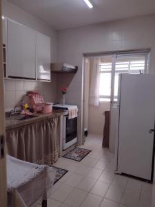 Apartamento Na Praia Das Astúrias في غوارويا: مطبخ مع دواليب بيضاء وثلاجة