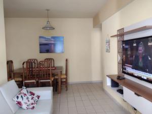 a living room with a television and a dining room at Apartamento Na Praia Das Astúrias in Guarujá