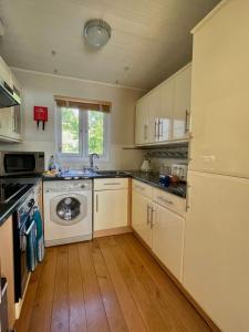 a kitchen with white cabinets and a washing machine at The Cotswolds Lakeside - Kinsale Lodge,Spring Lake in South Cerney