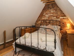 a bed in a room with a brick wall at 1 Fountain Cottages in Tarporley