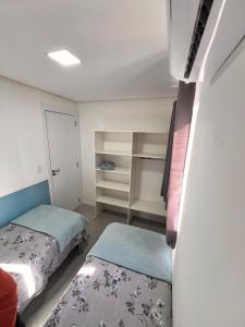 Habitación pequeña con 2 camas y armario. en Los Hermanos Residencial, en Florianópolis