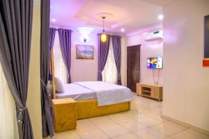 a bedroom with a bed with purple curtains and a tv at House 4 Guest House & Apartments in Lagos