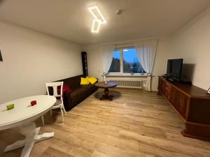 ein Wohnzimmer mit einem Sofa, einem TV und einem Tisch in der Unterkunft Ruhige Ferienwohnung im Saarland in Schiffweiler