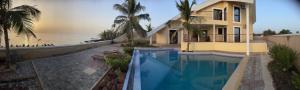 a house with a swimming pool in front of the ocean at Villa Bellevue in Ouoran