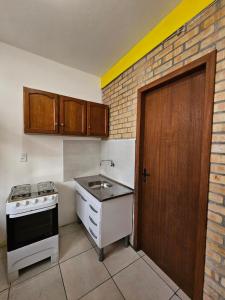 uma pequena cozinha com um fogão e um lavatório em Pousada Capricórnio em Guarda do Embaú