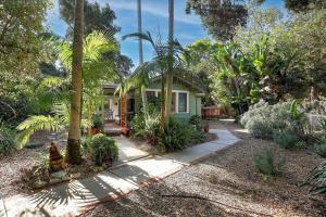 a yellow house with palm trees and a sidewalk at Hammonds Beach Haven in Santa Barbara