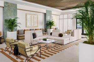 a living room with white furniture and palm trees at AC Hotel by Marriott Naples 5th Avenue in Naples