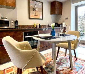 a kitchen with a table and chairs with wine glasses at Tetbury Cottage 