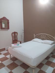 Cama blanca en una habitación con suelo de tablero de ajedrez en Hotel Conquistador Veracruz en Veracruz