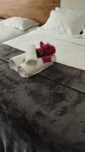 Una cama con una toalla y flores. en Apto 2 quartos - Condomínio Frente Mar, en Beberibe