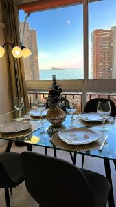 uma mesa com pratos e taças de vinho e vista para o oceano em Apartamento BENILOVE, en playa Benidorm em Benidorm