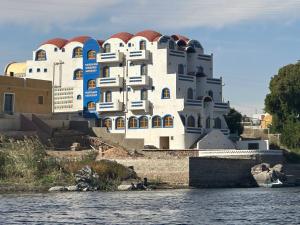 a large white building on the shore of a body of water at ACHERTOD NUBIAN HOTEL in Naj‘ al Maḩaţţah