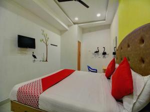 a bedroom with a bed with red pillows and a tv at OYO Flagship Ananda Inn in Madurai