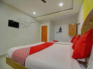 a bedroom with a large bed with red pillows at OYO Flagship Ananda Inn in Madurai