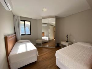 um quarto com 2 camas e um espelho em Quarto do Praia Brava Hotel em Florianópolis