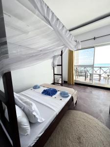 ein Schlafzimmer mit einem Himmelbett und einem großen Fenster in der Unterkunft Crystal Beach Nungwi in Nungwi