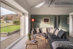 a living room with a couch and a large window at Tethera: Eco-Luxury Passivhaus on Ullswater in Watermillock