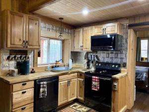 a kitchen with wooden cabinets and a black stove top oven at Couple Retreat Cabin-near Smoky Mountain Railroad-Hot Tub in Bryson City