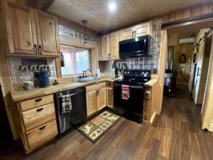 a kitchen with wooden cabinets and a black stove top oven at Couple Retreat Cabin-near Smoky Mountain Railroad-Hot Tub in Bryson City