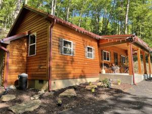 a log cabin in the woods with a porch at Couple Retreat Cabin-near Smoky Mountain Railroad-Hot Tub in Bryson City
