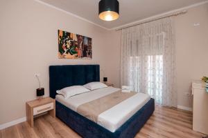 Schlafzimmer mit einem Bett mit blauem Kopfteil und einem Fenster in der Unterkunft Loris Apartaments 205 in Durrës