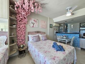 ein Schlafzimmer mit einem Bett mit rosa Blumen drauf in der Unterkunft Mar de Cerejeira in Arraial do Cabo