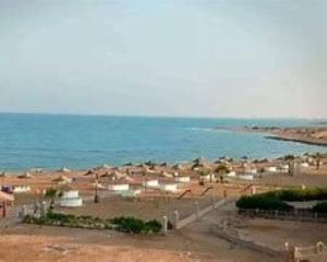 a beach with a bunch of umbrellas and the ocean at راس سدر للعائلات in Ras Sedr