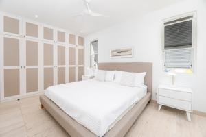 une chambre blanche avec un grand lit et deux fenêtres dans l'établissement Porters Place 13 villa, à Saint James 9 autres photos