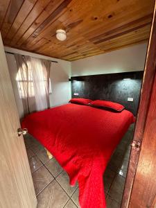 a red bed in a room with a wooden ceiling at The valley in Creel