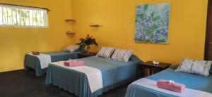 three beds in a room with yellow walls at Gran Gavilán del Sarapiquí Lodge in Sarapiquí