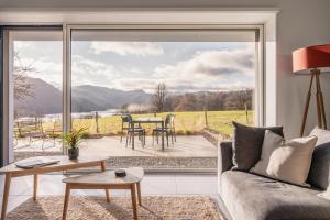 a living room with a couch and a large window at Tethera: Eco-Luxury Passivhaus on Ullswater in Watermillock