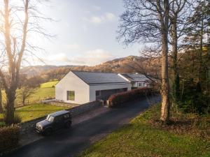 a car parked on a road next to a white house at Tethera: Eco-Luxury Passivhaus on Ullswater in Watermillock